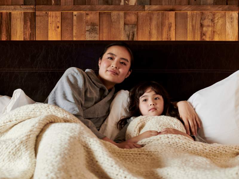 Mother and daughter lounge in their bed