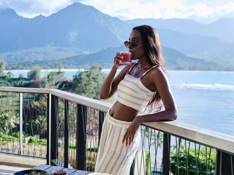 Woman haven a cocktail with landscape behind her
