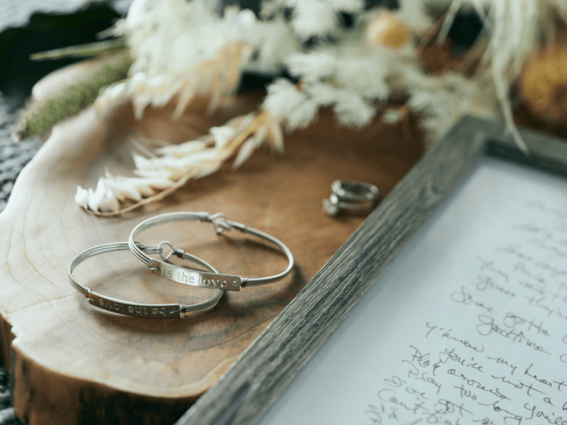 Two metal bracelets next to a wood frame hand written letter