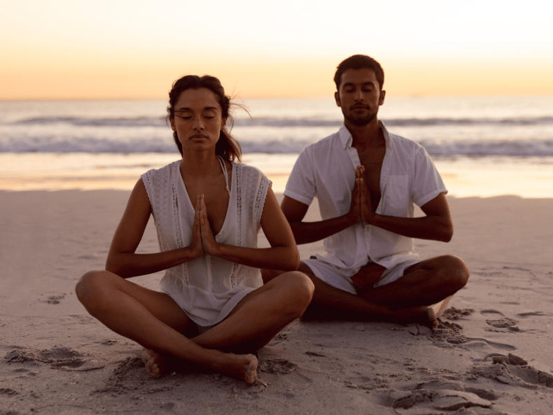 Two people meditating on a beach