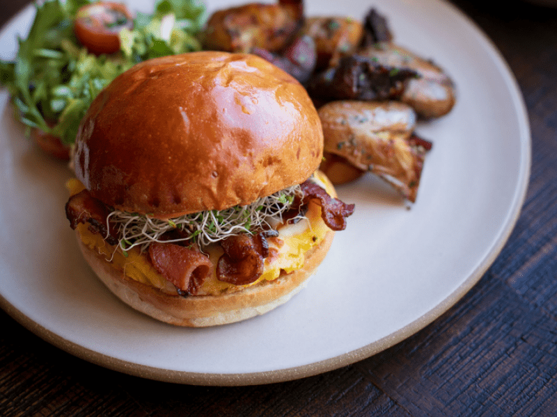 A breakfast burger with side salad, roasted potatoes, and coffee