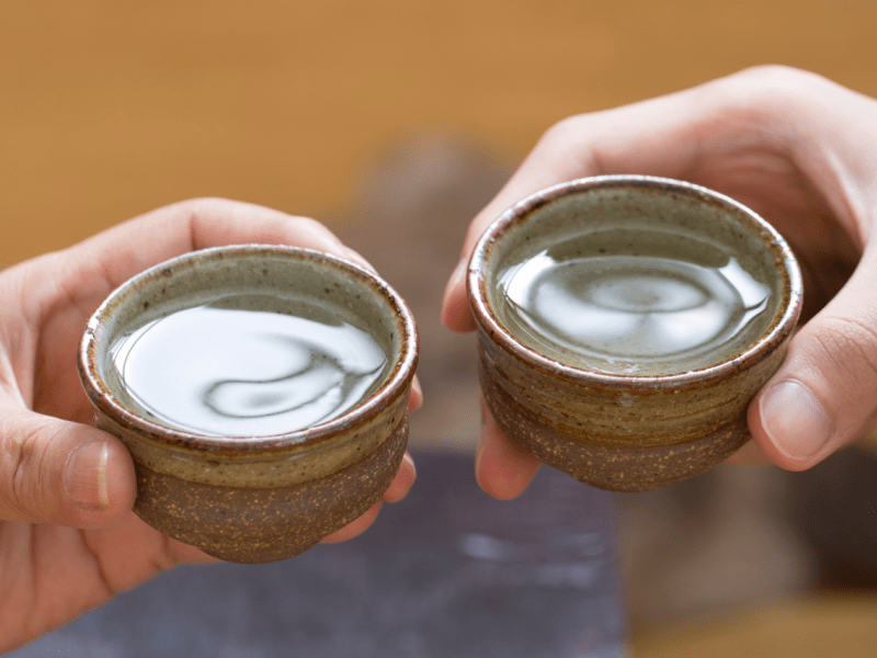 Two people holding cups of sake