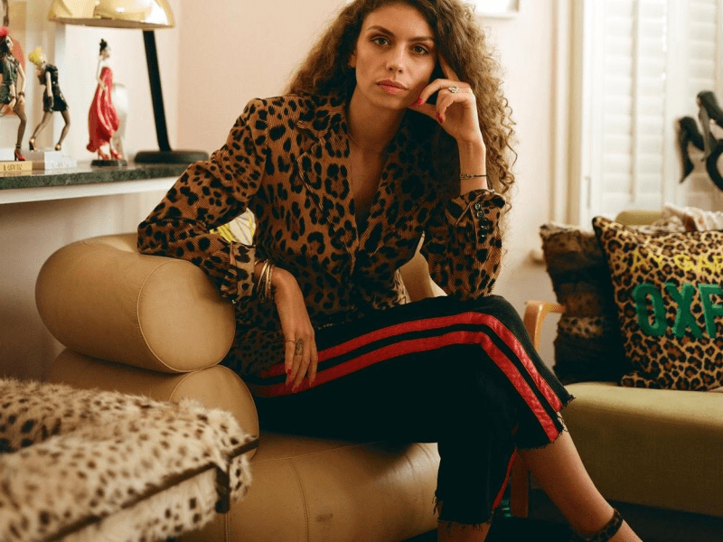 Brunette woman wearing a leopard print shirt poses for the camera while seated