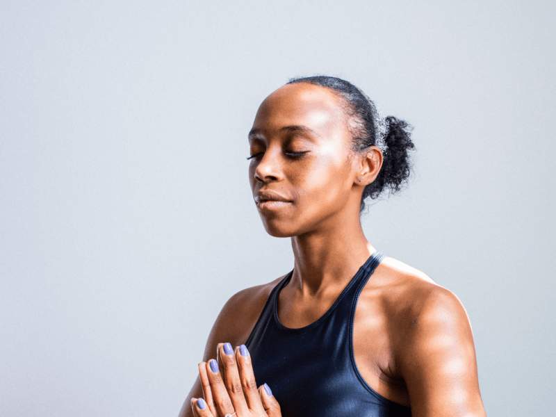 Person holding their hands together in front of their chest with their eyes closed