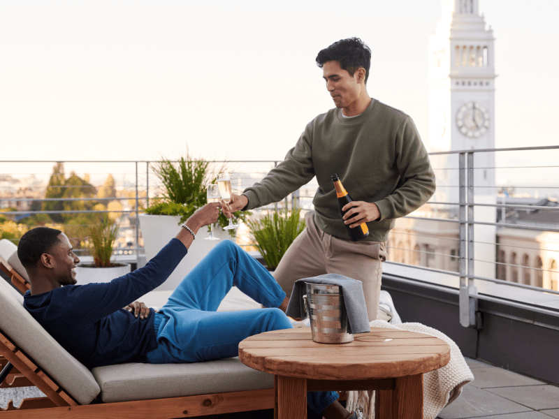 Two people sharing a glass of champagne on an outdoor patio
