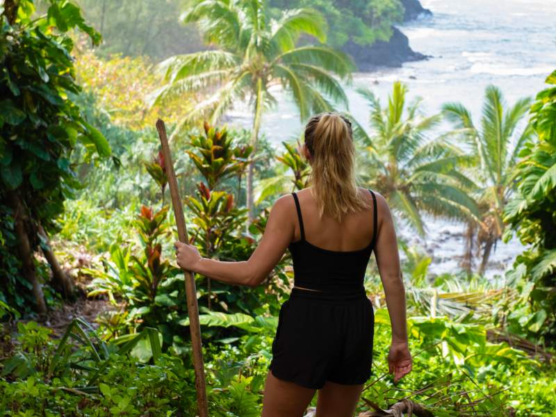 Person hiking through a jungle with a walking stick