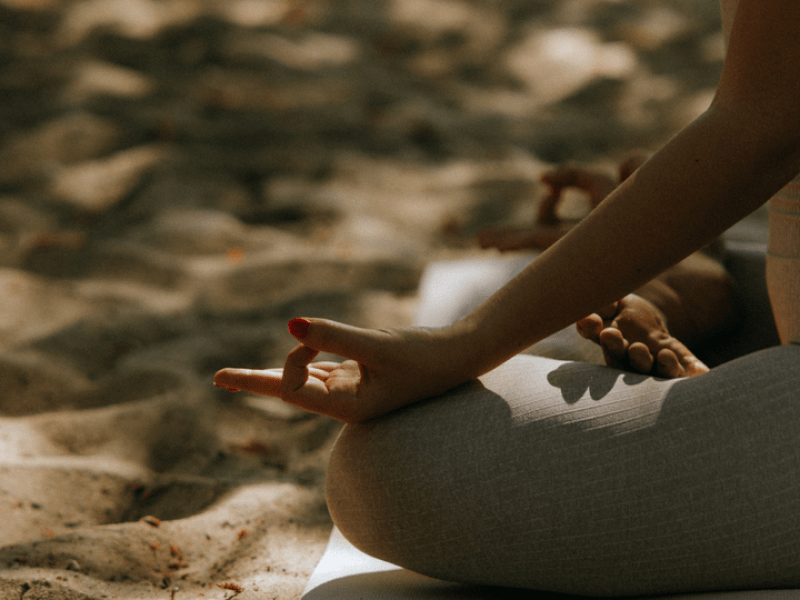woman sitting in a yoga pose by the water