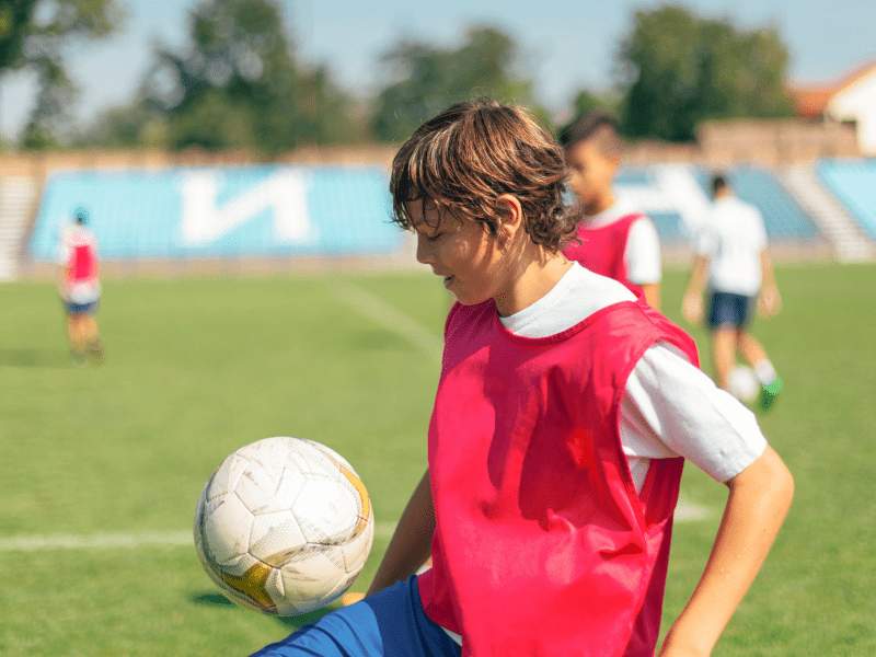 Et barn på en fodboldbane med en fodbold