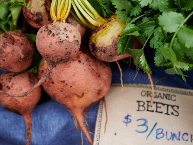 Organic beets set out for purchase, a sign reads Organic Beets three dollars per bunch