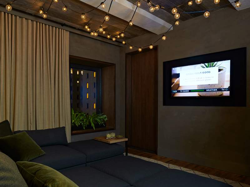 Dimly lit room with a large couch and wall mounted tv