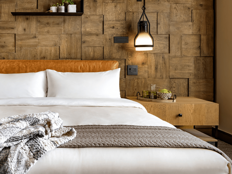 A made bed with white sheets surrounded by modern yet rustic décor