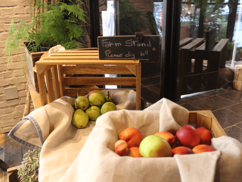 A farm stand with a basket of peaches and pears