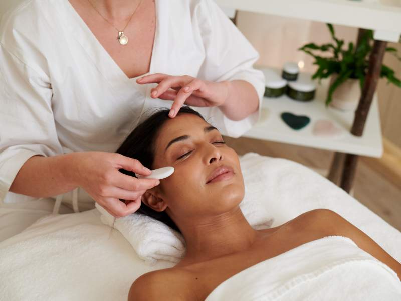 A woman smiles while receiving a massage at a spa.