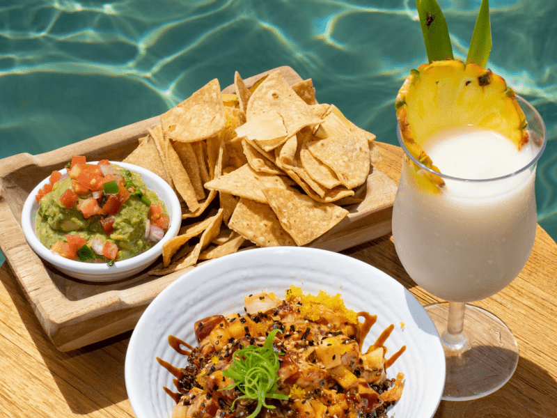 Poke bowl with chips and dip and a pina colada, by the poolside