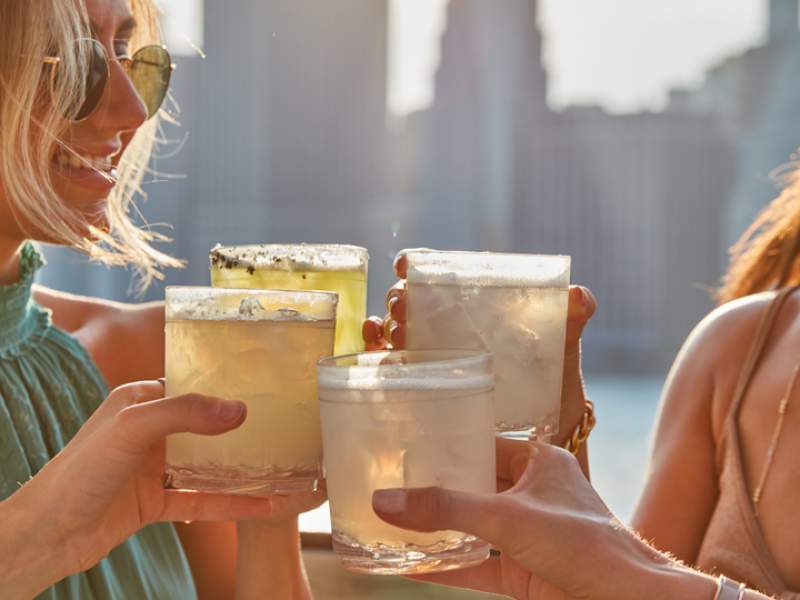 Four people cheers their drinks on the harriets rooftop patio