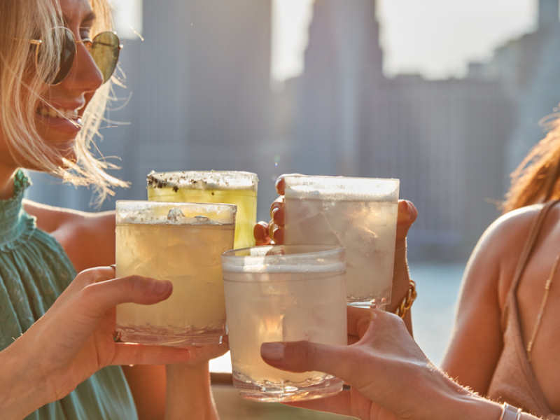 Four people cheers their drinks on the harriets rooftop patio