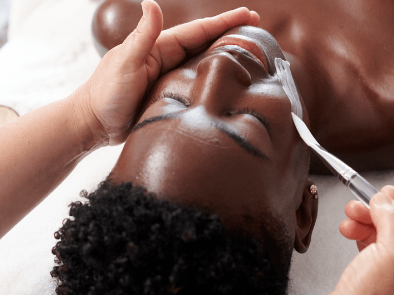 A woman lying face up on a massage bed receives a relaxing spa facial