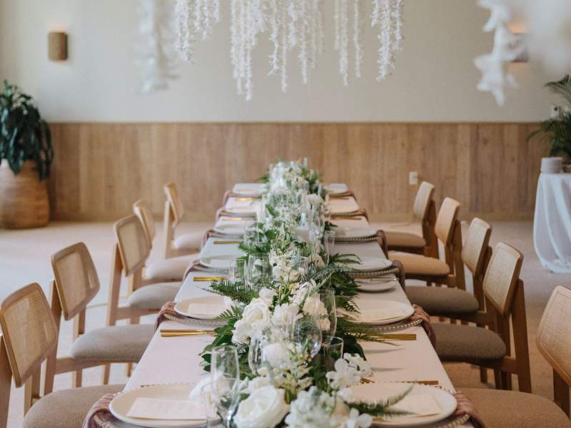table dressée avec des assiettes blanches et un chemin de table en fleurs blanches