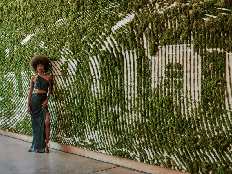 Woman stand in front of the 1Hotel West Hollywood plant sign 