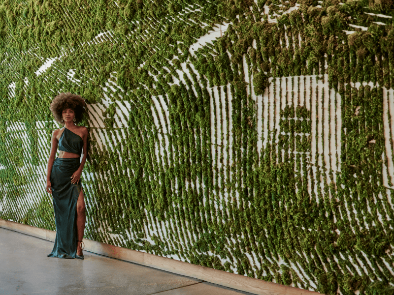 Woman stand in front of the 1Hotel West Hollywood plant sign 