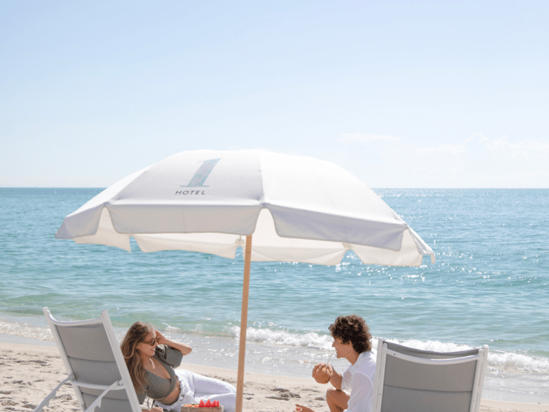 Two people sitting under an umbrella on the beach