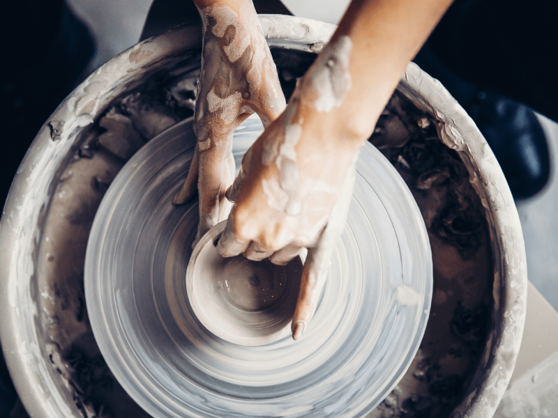 hands shaping pottery on a pottery wheel
