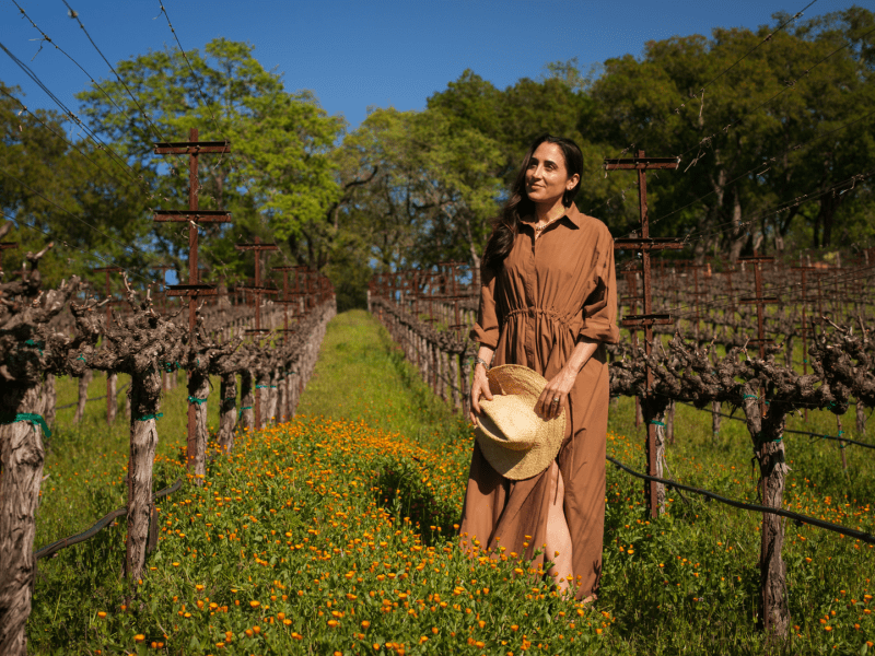 Person standing in a field holding a hat