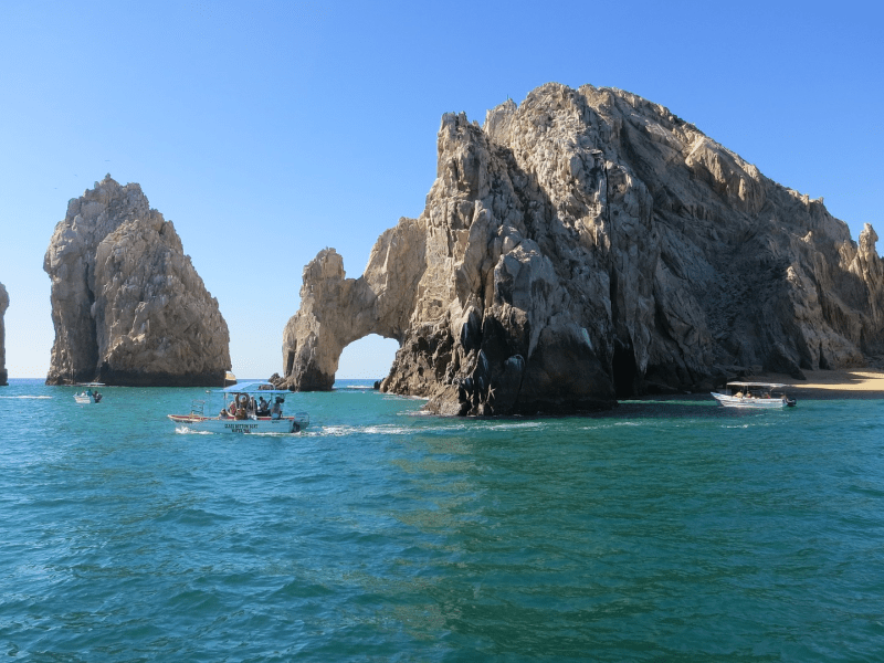 People on a boat in the water near rock arches