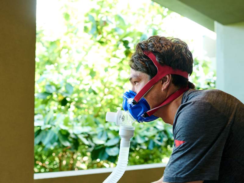 Man wearing v02 oxygen mask looking out a window