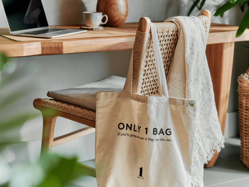 1 Hotels themed bag hanging on the back of a desk chair