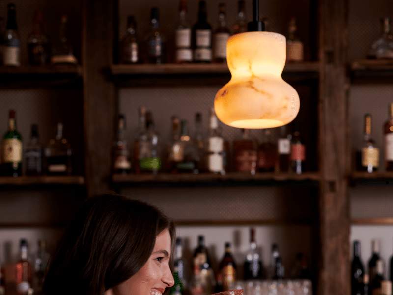 Person smiling with a drink in hand at the 1 Hotel West Hollywood lobby bar