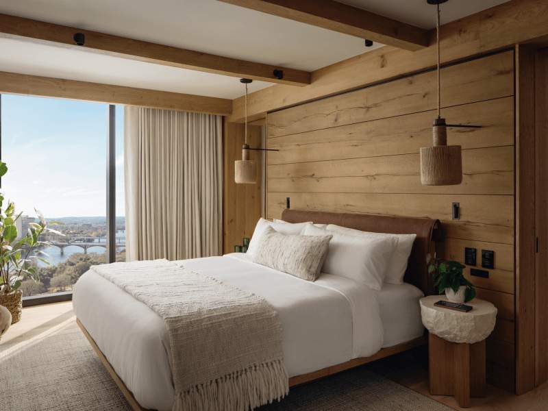 Cama grande num quarto com interior em madeira e uma janela ampla