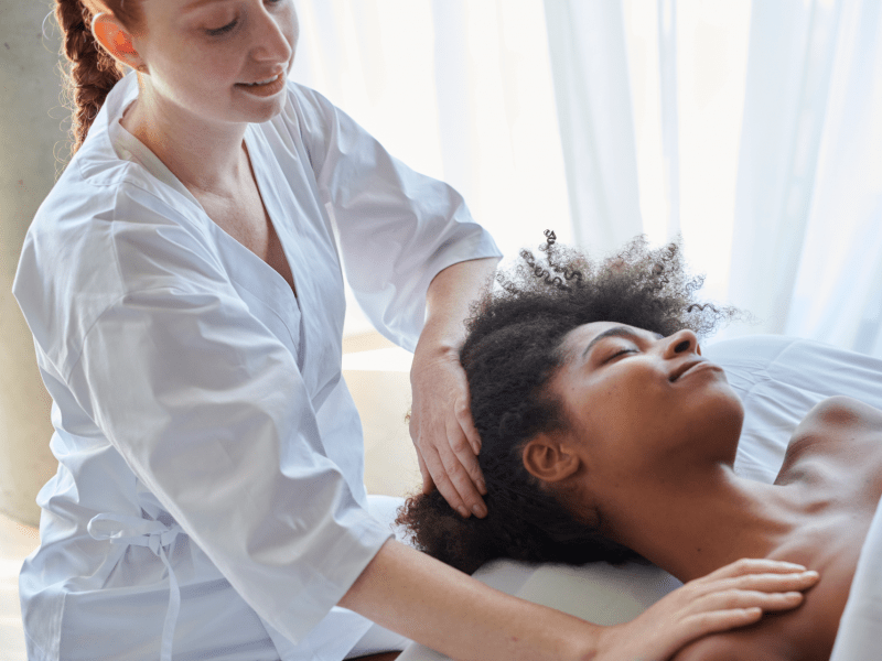 A woman receives a shoulder massage as she lies face up on a massage table