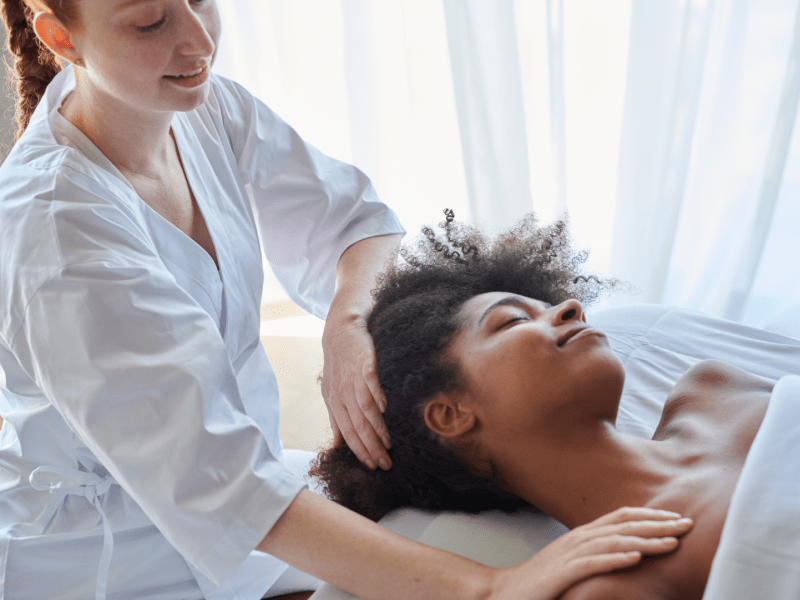 A woman receives a shoulder massage as she lies face up on a massage table