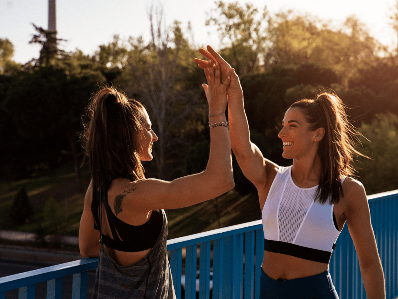 Two people high fiving outside - on running