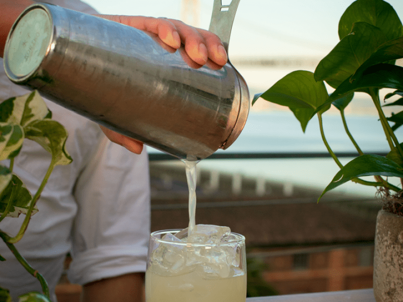 Bartender pouring a margarita into a glass of ice