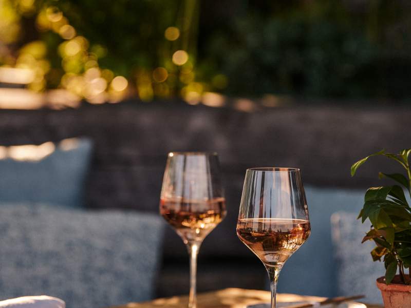 Deux verres à vin rosé sur une table en bois chez Harriet's Rooftop