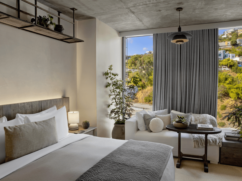 Neutral colored hotel room with window looking out to trees