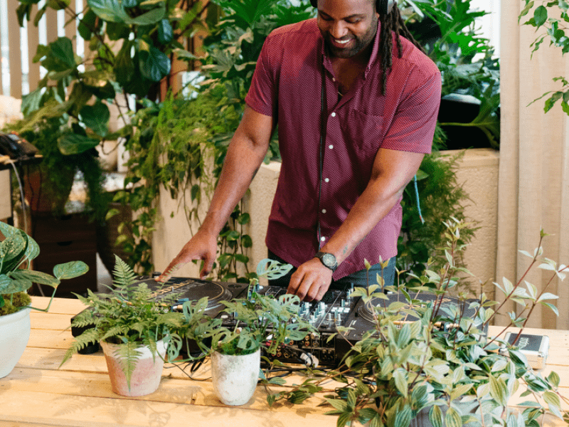 Person using a turntable with plants next to it