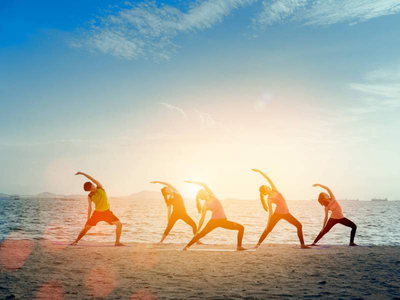 A group of people doing yoga on a beach