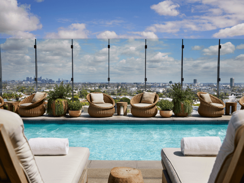 A view of the rooftop pool from between two poolside lounge chairs