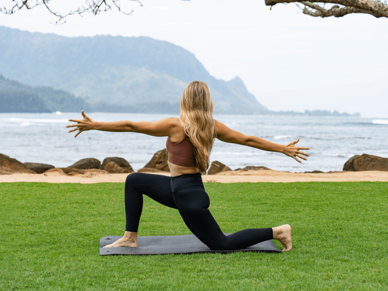 Woman doing yoga position with ocean and hills in the background