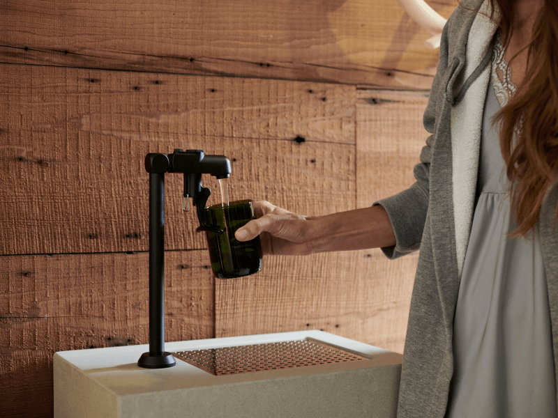 A woman fills her cup with water from a dispenser.