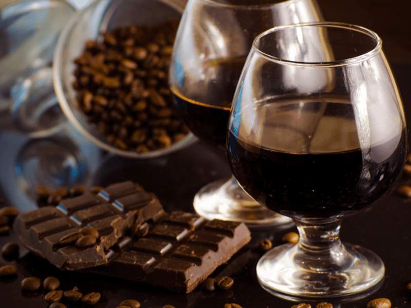 Un vaso de ron, una tableta de chocolate rota y granos de cacao