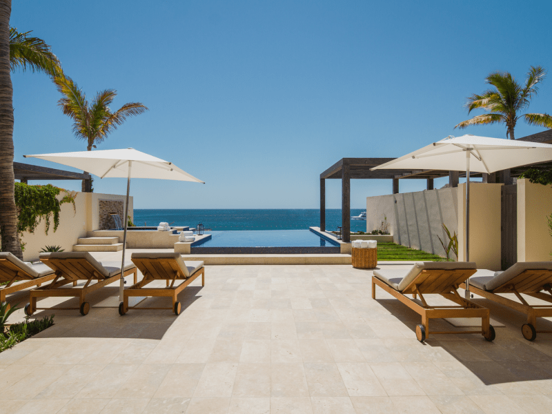 Outdoor patio with reclining lounge chairs overlook a view of the ocean