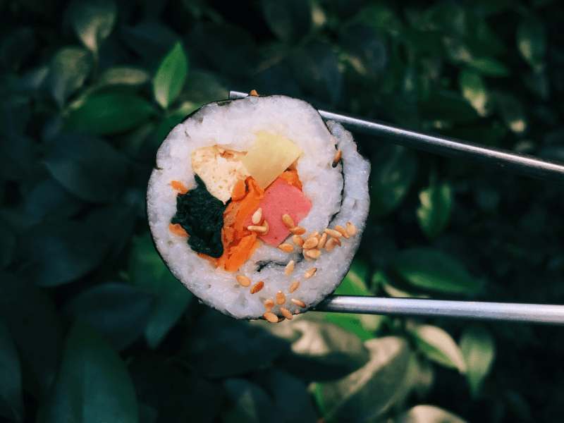A sushi roll held in a pair of chopsticks