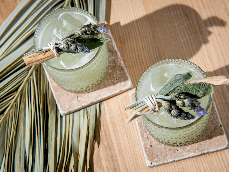 Two green colored cocktails with sage garnishes