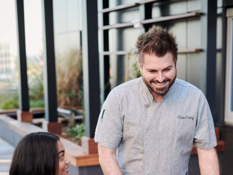 Culinary director Chris Crary delivers food to a table of excited looking guests at 1 Hotels Nashville