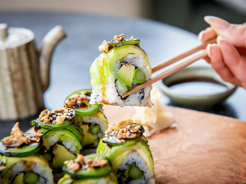 Person eating a sushi roll with chopsticks