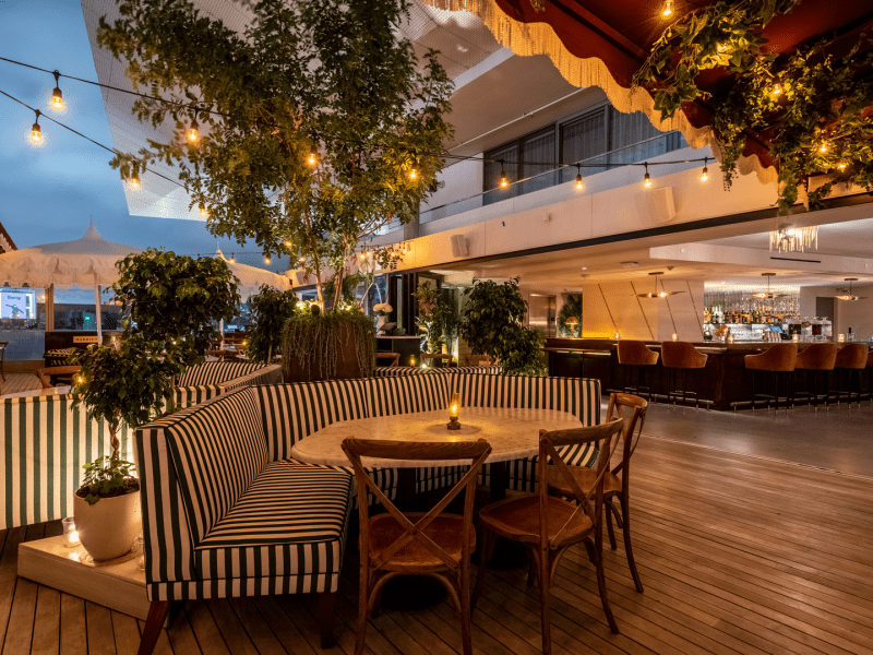 Outdoor dining area at dusk with striped benches